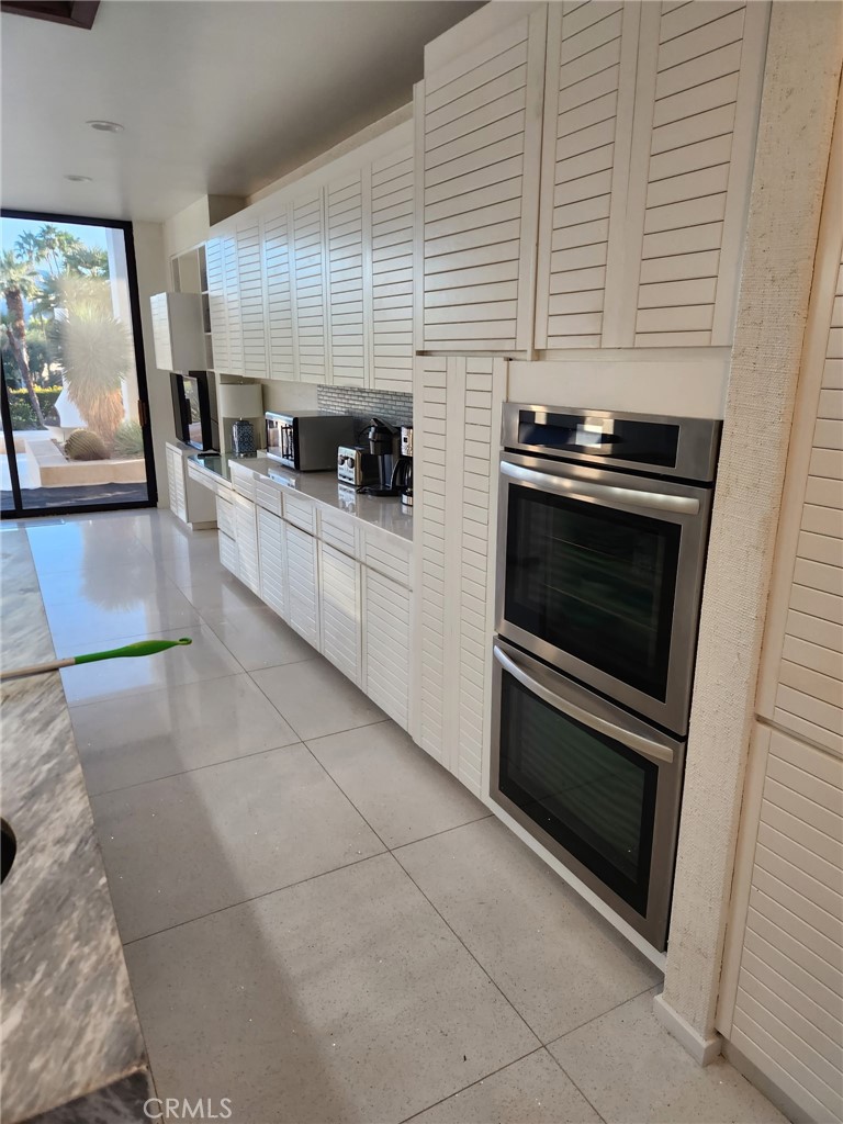 70955 Tamarisk Lane Rancho Mirage, CA 92270 - Photo 19 of 42 a kitchen with stainless steel appliances kitchen island granite countertop a stove a sink and a microwave