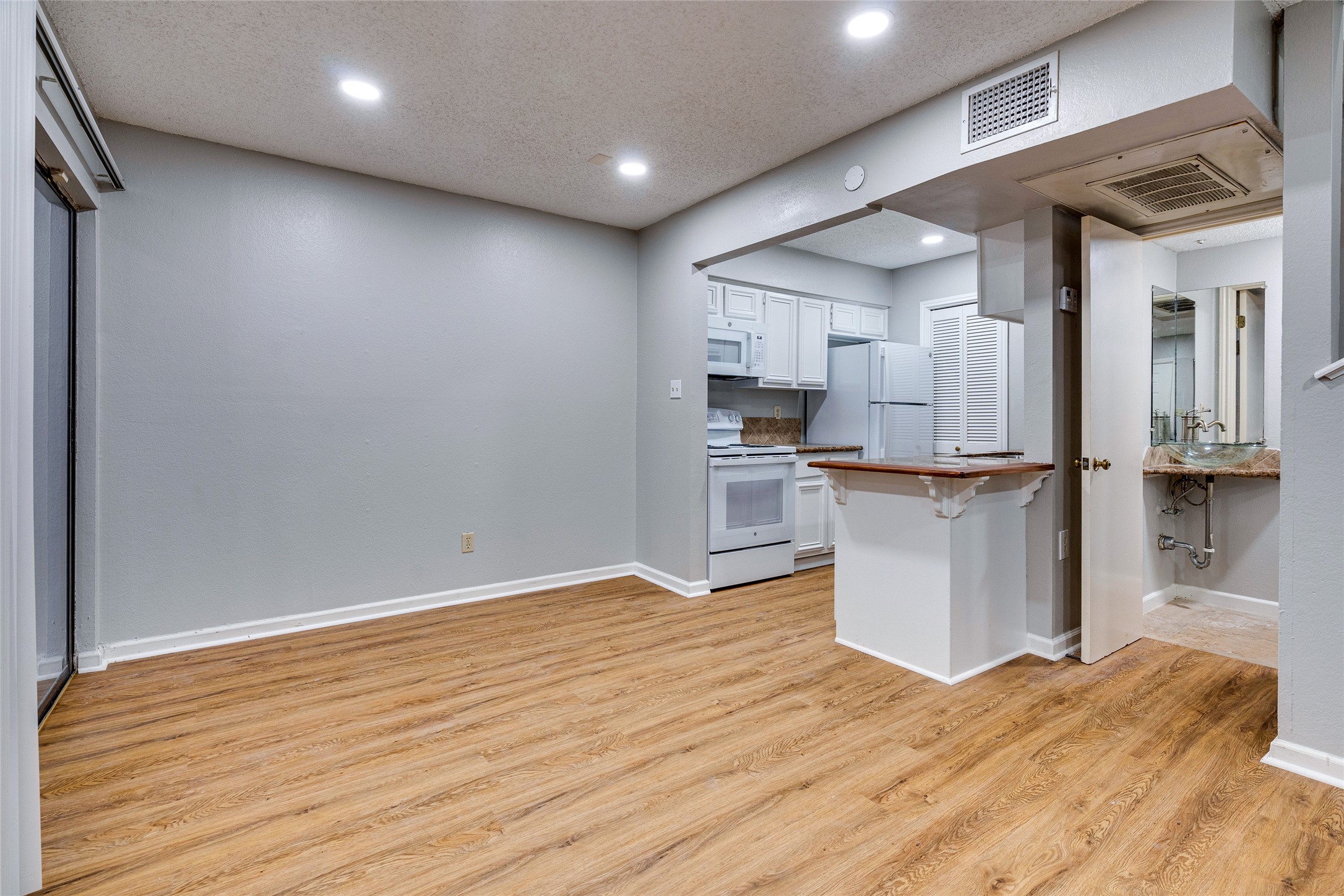 1808 Rio Grande Street, Unit 6 Austin, TX 78701 - Photo 3 of 29 Kitchen with white cabinetry, white appliances, recessed lighting, a peninsula, and light wood-style floors