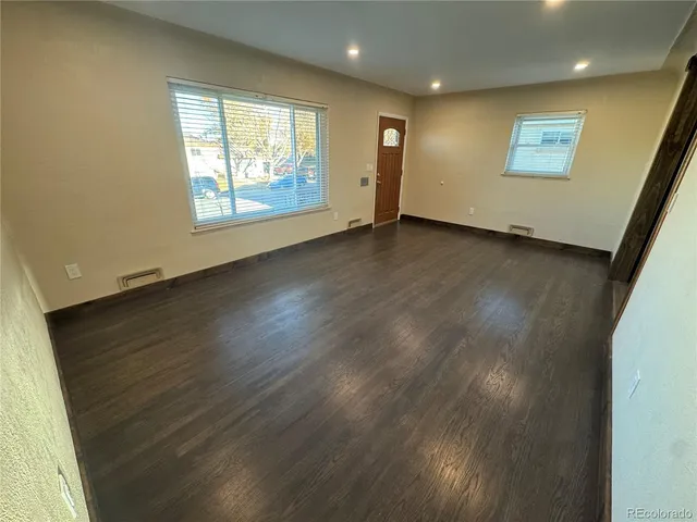 an empty room with wooden floor and windows