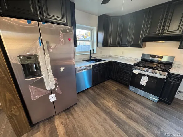 a kitchen with stainless steel appliances granite countertop a refrigerator a sink and a stove