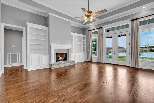 a view of an empty room with wooden floor and a ceiling fan