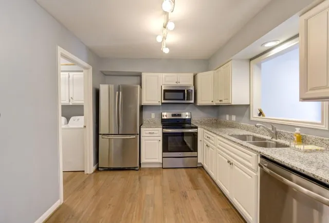 a kitchen with a refrigerator a stove top oven a sink and dishwasher with wooden floor