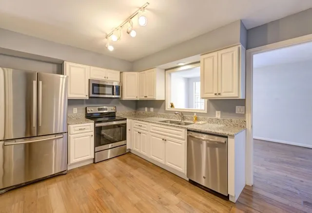 a kitchen with granite countertop white cabinets and stainless steel appliances