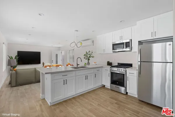 a kitchen with cabinets stainless steel appliances and wooden floor