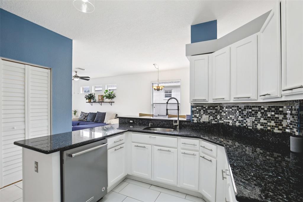 7164 Spikerush Court Lakewood Ranch, FL 34202 - Photo 13 of 36 a kitchen with granite countertop white cabinets and black appliances