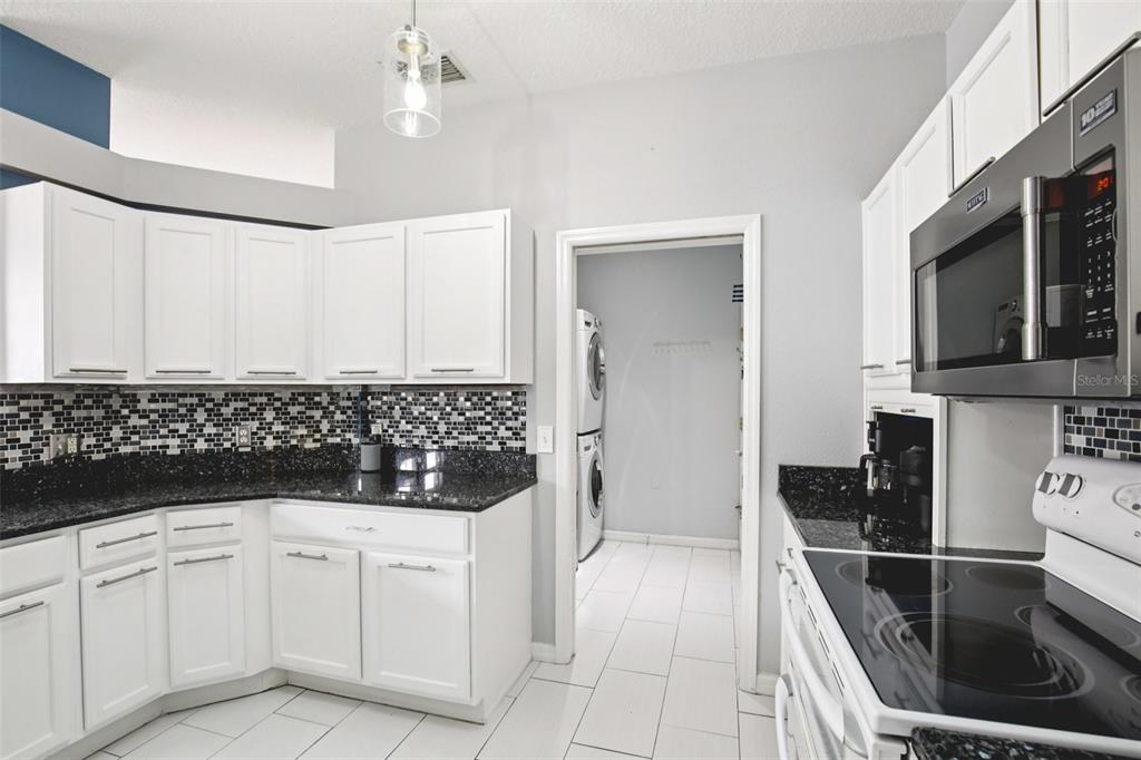 7164 Spikerush Court Lakewood Ranch, FL 34202 - Photo 16 of 36 a kitchen with white cabinets and black appliances