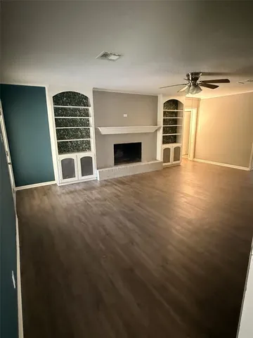 a big room with wooden floor fireplace and windows