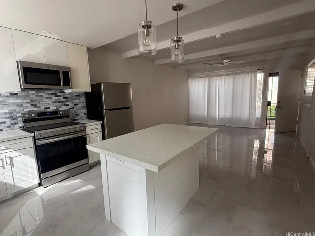 a kitchen with stainless steel appliances kitchen island granite countertop a stove and a refrigerator