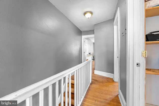 a view of a hallway with wooden floor and interior of bathroom