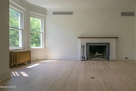 a view of an empty room with a window and fireplace