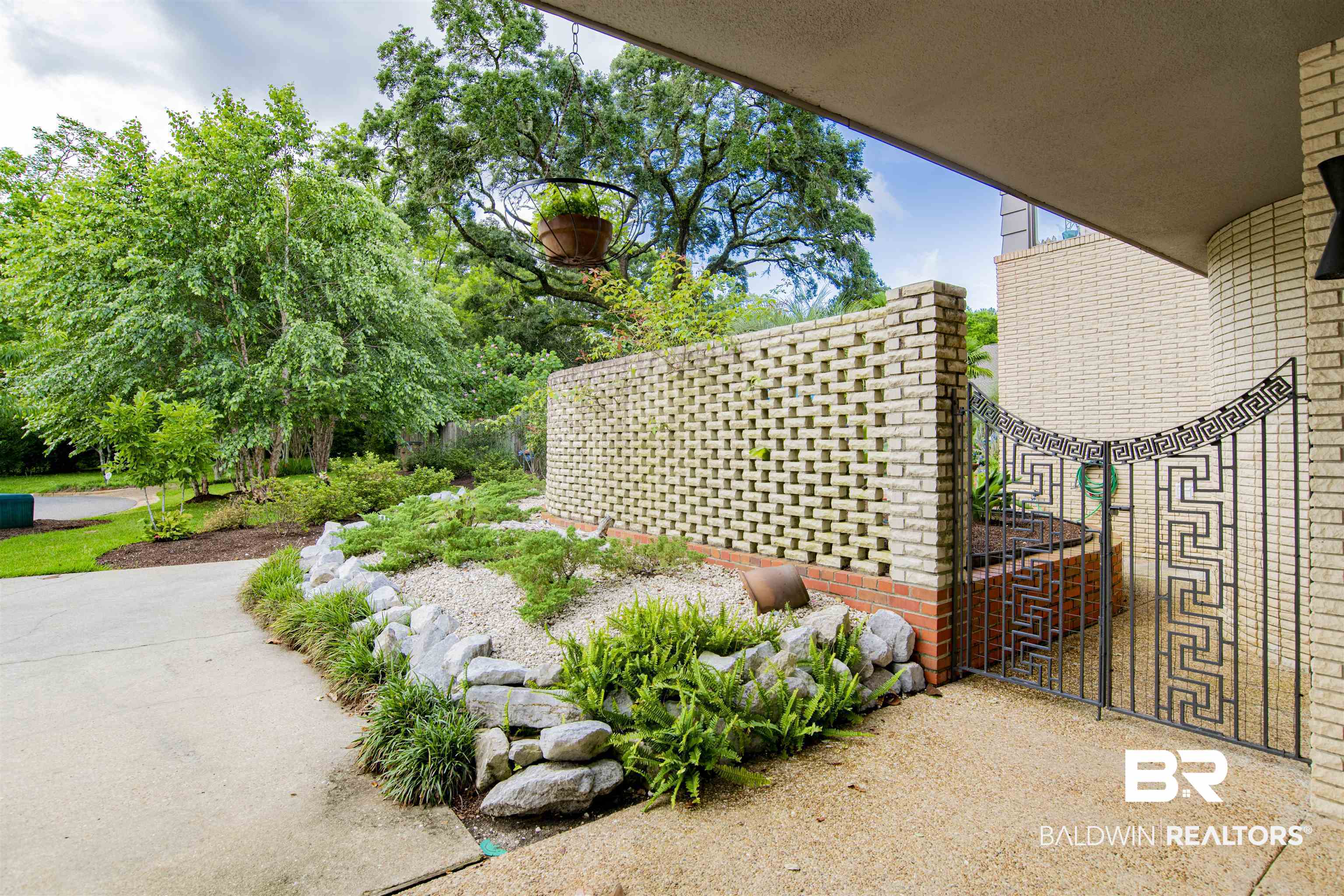 809 Bernard Circle Mobile, AL 36693 - Photo 73 of 75 Landscaped entryway featuring a decorative metal gate, brick screen wall, and a curved concrete path