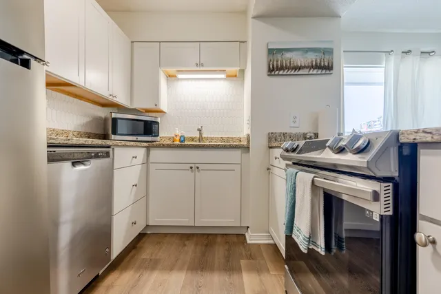 a kitchen with stainless steel appliances granite countertop a stove a sink and a refrigerator