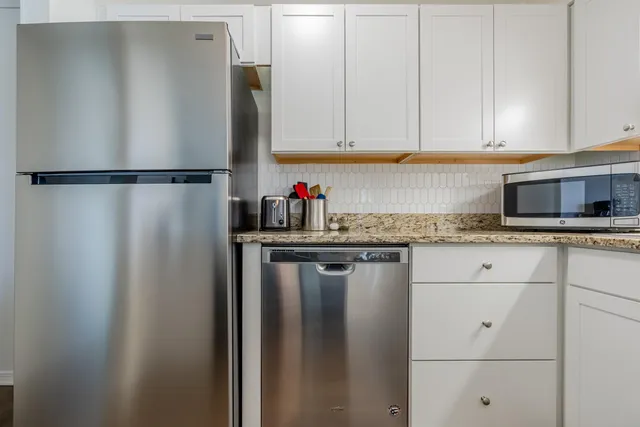 a kitchen with stainless steel appliances white cabinets and a refrigerator