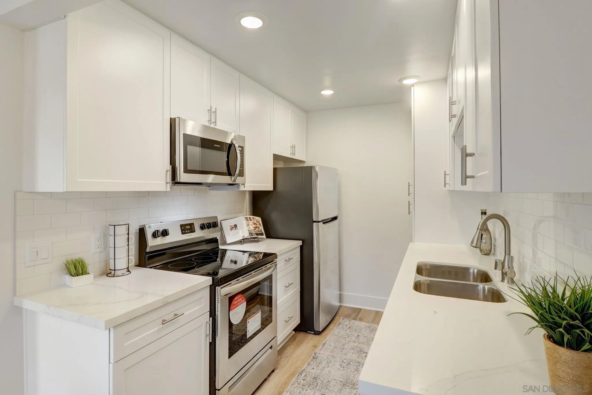 8660 Via Mallorca, Unit B La Jolla, CA 92037 - Photo 7 of 27 a kitchen with stainless steel appliances a stove a sink a refrigerator a microwave a refrigerator white cabinets and wooden floor