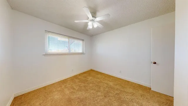 an empty room with a chandelier fan and windows