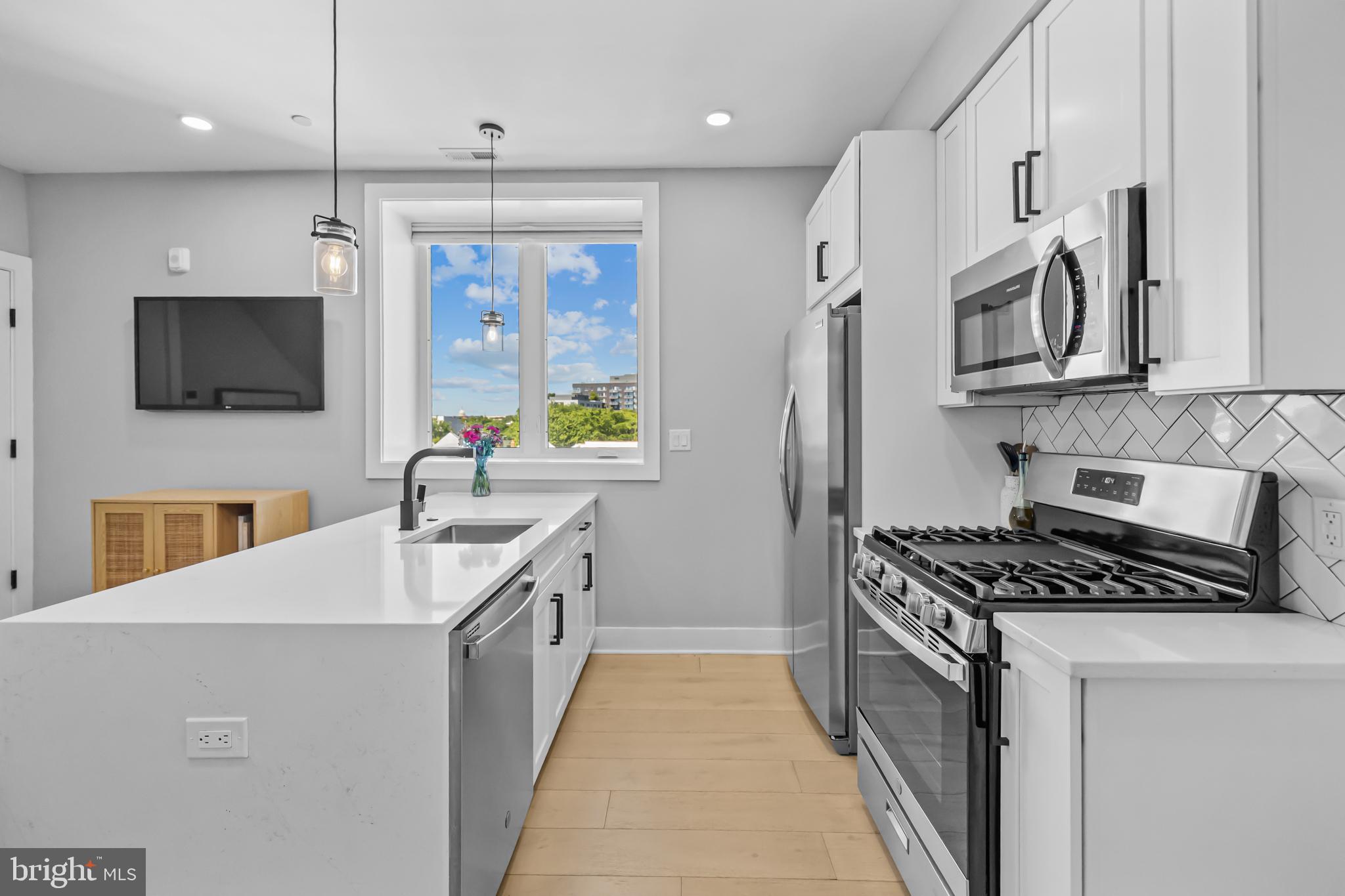 1915 H Street Northeast, Unit PH1 Washington, DC 20002 - Photo 10 of 21 a kitchen with stainless steel appliances a sink stove and refrigerator