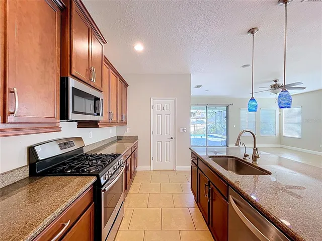 a kitchen with granite countertop stainless steel appliances a sink stove and cabinets