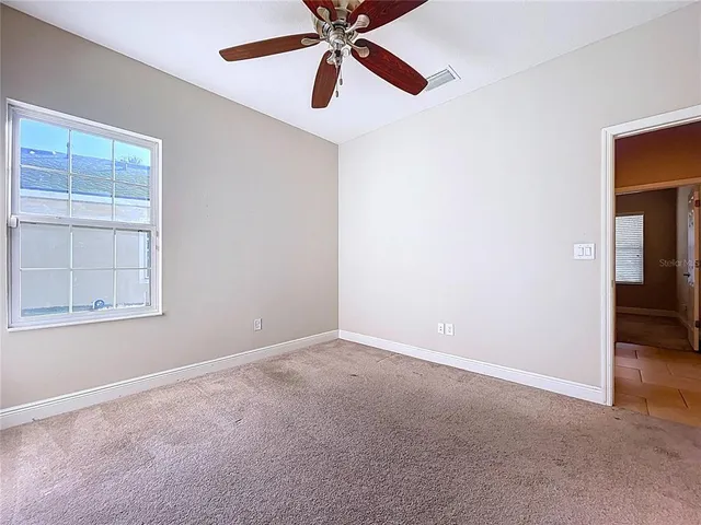 an empty room with windows and fan