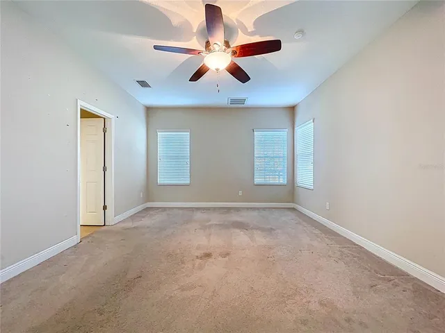 an empty room with windows and fan