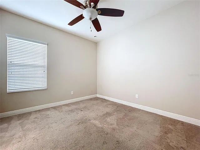an empty room with a window and a fan
