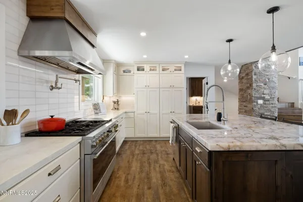 a kitchen with kitchen island granite countertop a sink cabinets and wooden floor
