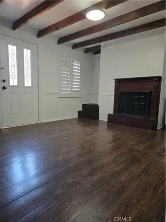 an empty room with wooden floor fireplace and windows
