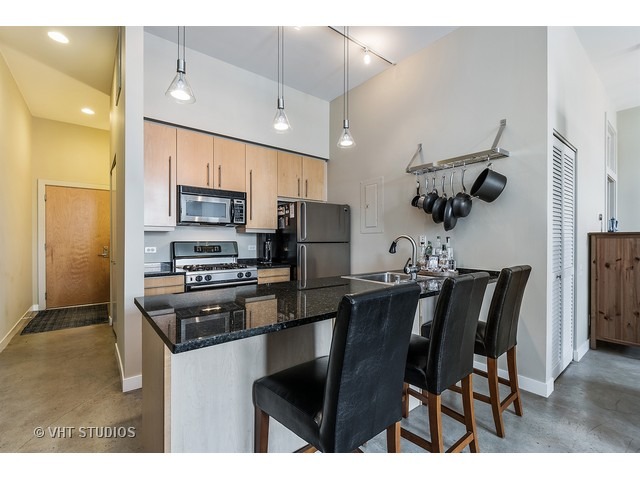939 West Madison Street, Unit 604 Chicago, IL 60607 - Photo 5 of 10 a kitchen with stainless steel appliances granite countertop a stove top oven a refrigerator a sink and a microwave