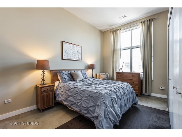 939 West Madison Street, Unit 604 Chicago, IL 60607 - Photo 7 of 10 a bedroom with a bed and a night stand