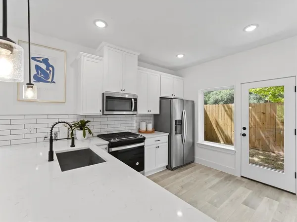 a kitchen with stainless steel appliances a refrigerator a sink a stove and cabinets