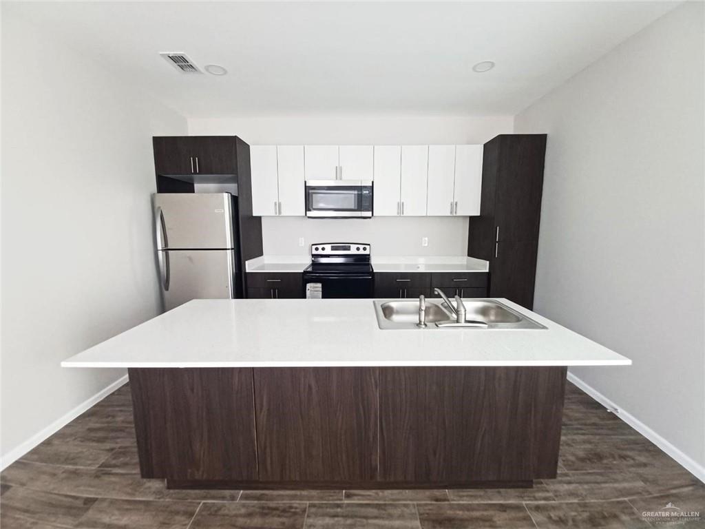 907 East Starr Road, Unit D Mercedes, TX 78570 - Photo 6 of 10 a kitchen with kitchen island a refrigerator sink and stove