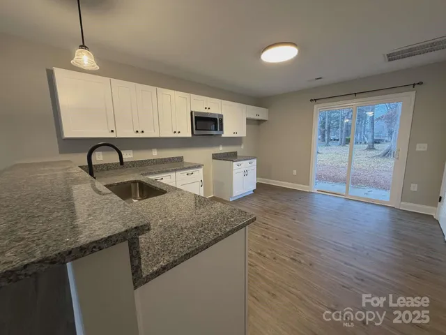 a kitchen with granite countertop a sink a counter top space and cabinets