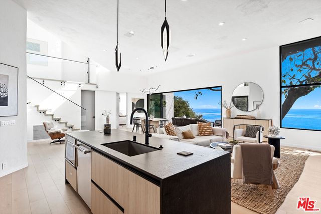 a kitchen with stainless steel appliances kitchen island granite countertop a sink and a stove with wooden floor