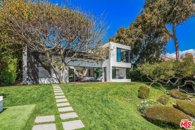 a view of a house with a big yard plants and large trees