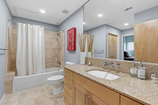 a bathroom with a granite countertop sink a toilet a mirror a vanity and shower