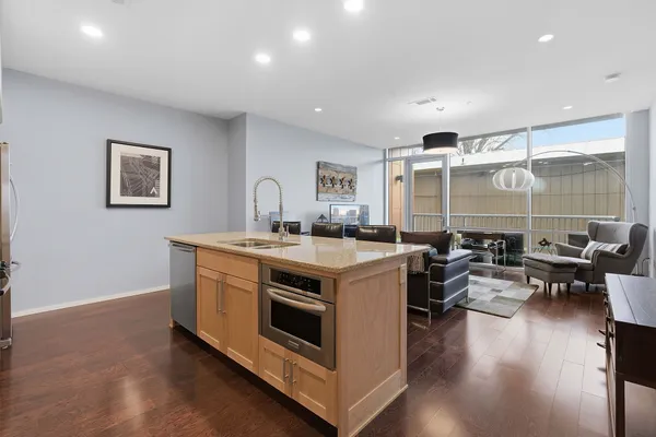 a view of kitchen with stainless steel appliances granite countertop a stove and a wooden floors