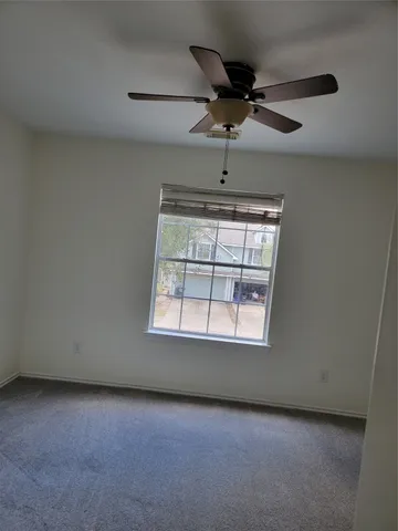 an empty room with a ceiling fan and window