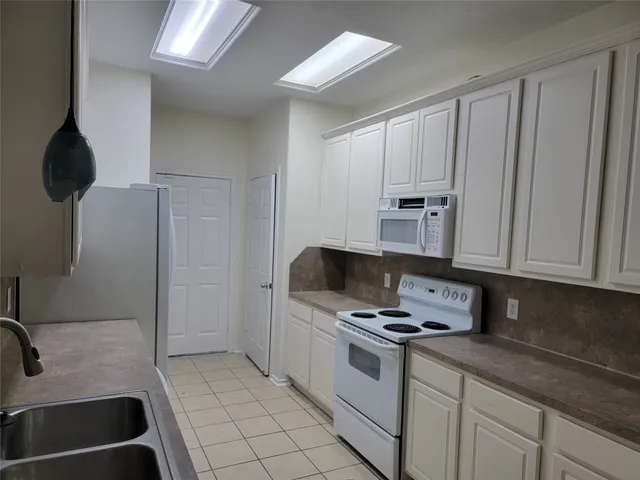 a kitchen with white cabinets a sink and a stove