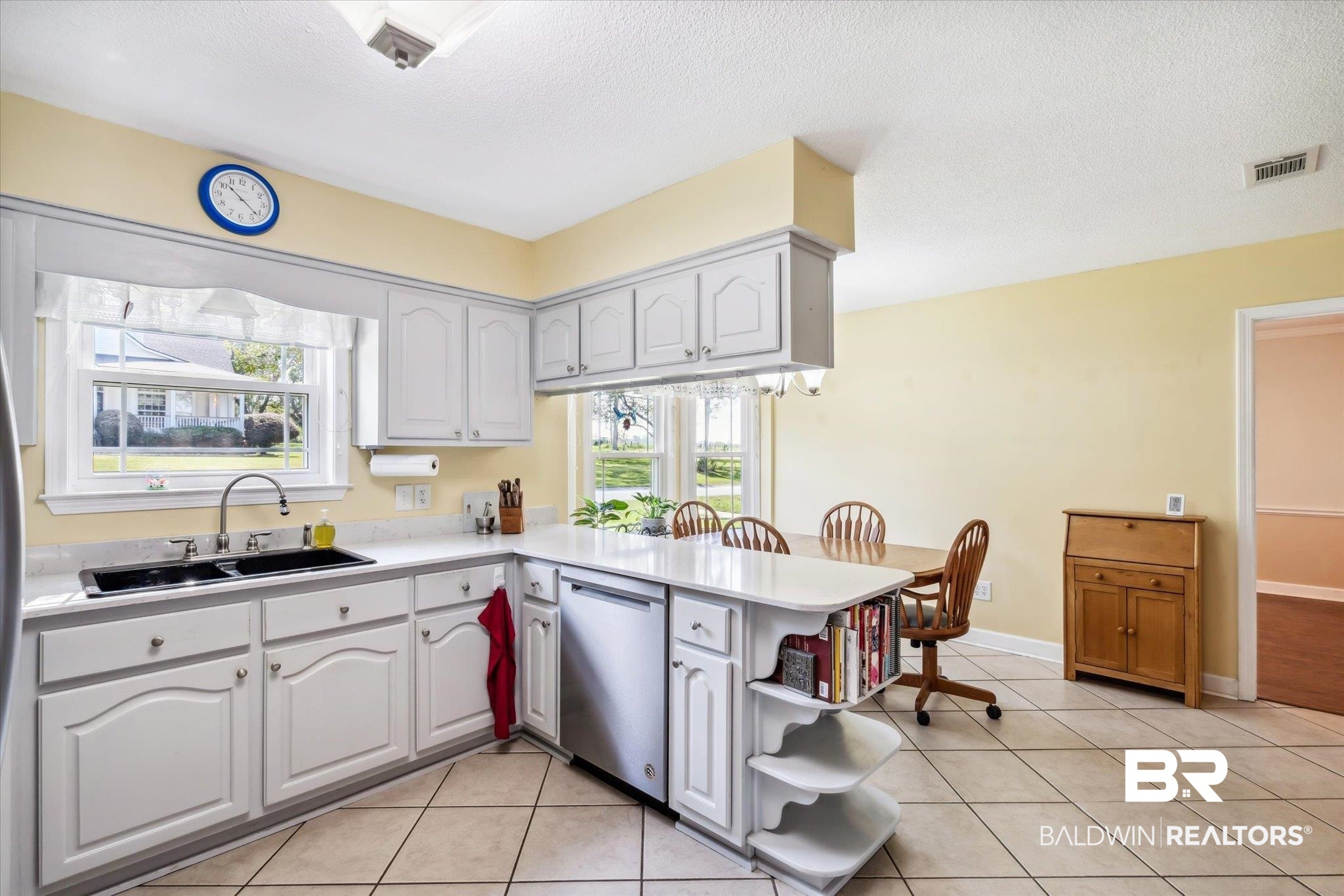 8710 Three Notch Road Mobile, AL 36619 - Photo 7 of 30 Kitchen with light tile patterned flooring, stainless steel dishwasher, white cabinets, sink, and kitchen peninsula