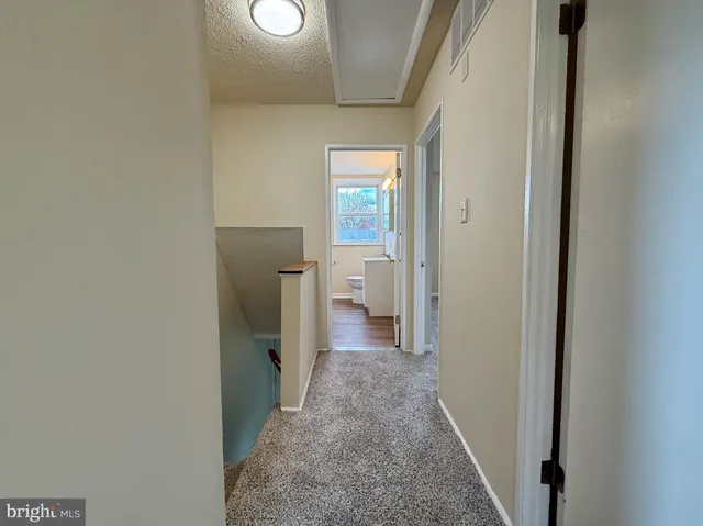 a view of a hallway with wooden floor and a bathroom