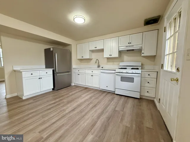 a kitchen with stainless steel appliances granite countertop a stove top oven a sink dishwasher and a refrigerator with wooden floor