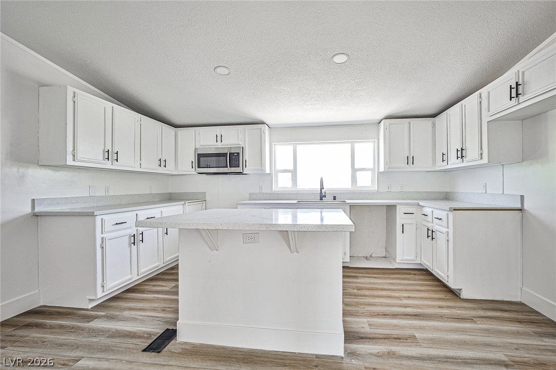 273 Aztec Lane Henderson, NV 89015 - Photo 5 of 28 White cabinetry, solid surface countertops, and an island define this well-appointed kitchen space.