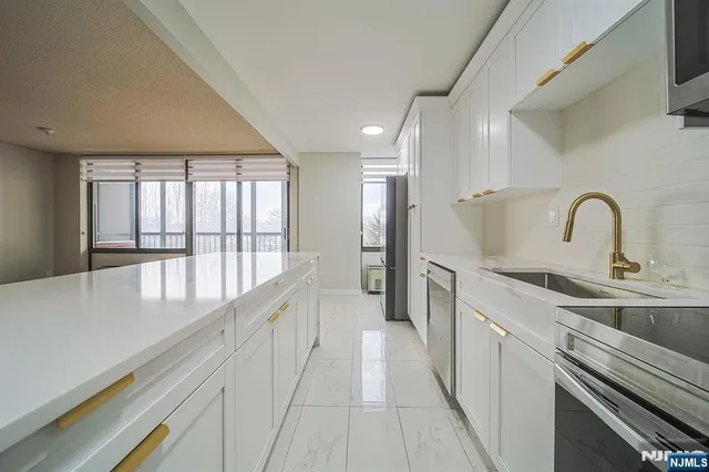 a large kitchen with kitchen island a large window a sink and stainless steel appliances