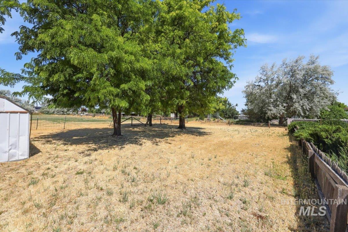 1311 North Middleton Road Nampa, ID 83651 - Photo 48 of 49 Expansive outdoor area featuring mature trees providing natural shade, a partial perimeter fence, and a utility shed