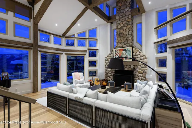 a living room with furniture a fireplace and a floor to ceiling window