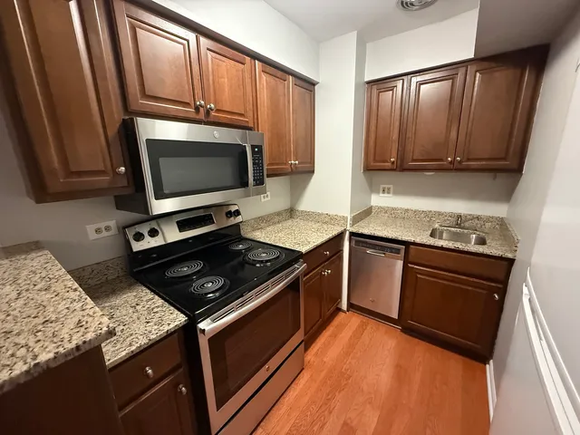 a kitchen with granite countertop wooden cabinets and a stove top oven