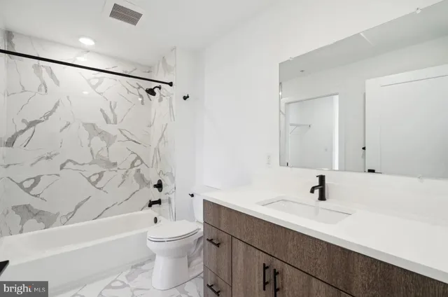 a bathroom with a sink a toilet a mirror a bathtub and shower