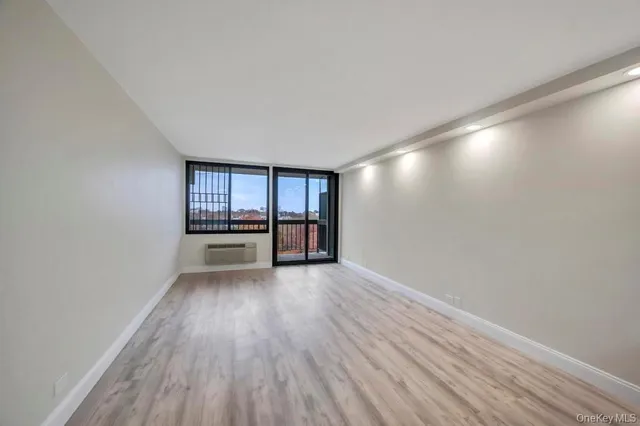 a view of an empty room with a window and wooden floor