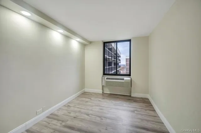 a view of an empty room with a window and wooden floor