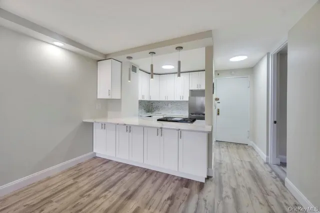 a kitchen with a hard wood floor white cabinets and stainless steel appliances