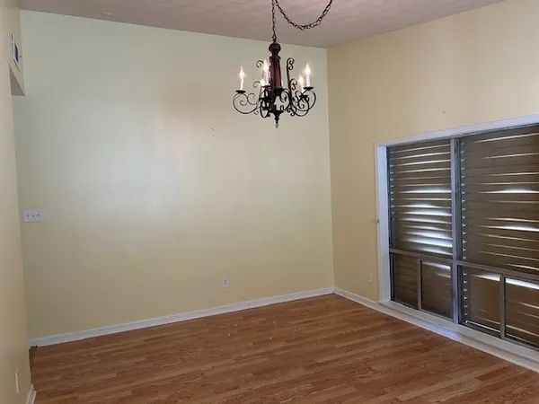 a view of a chandelier in an empty room with wooden floor and windows